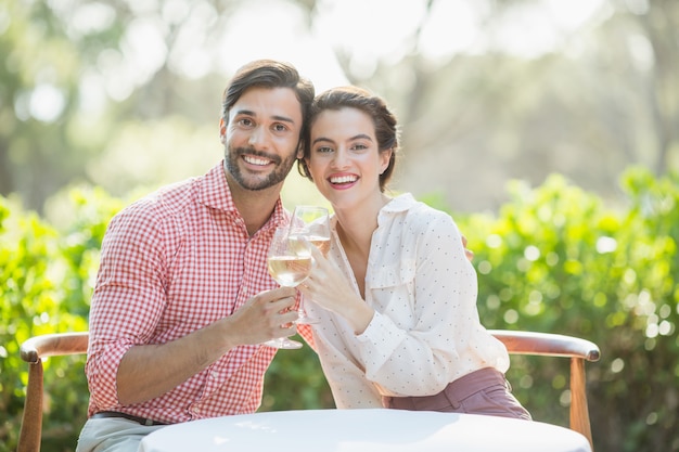 Couple toasting wine glasses while sitting in restaurant