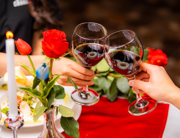 Photo a couple toasting with wine glasses at a table