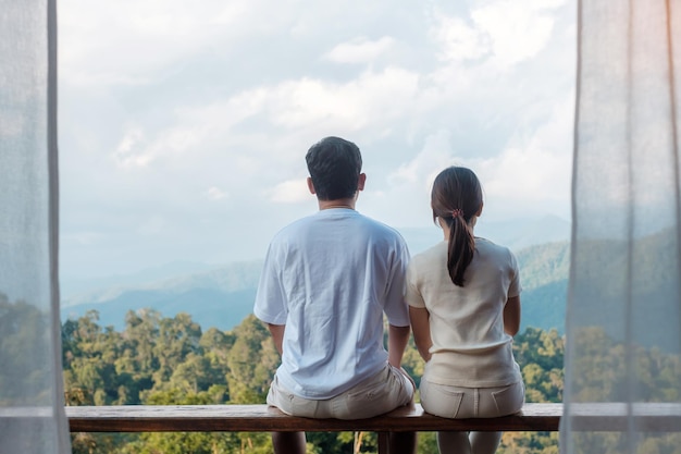 Couple tourist relaxing and looking mountain view at countryside home or homestay in the morning. Vacation, together travel, honeymoon, blogger, journey, trip and relaxing concept