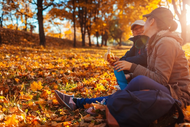 Couple of tourists with backpacks having rest in autumn forest 