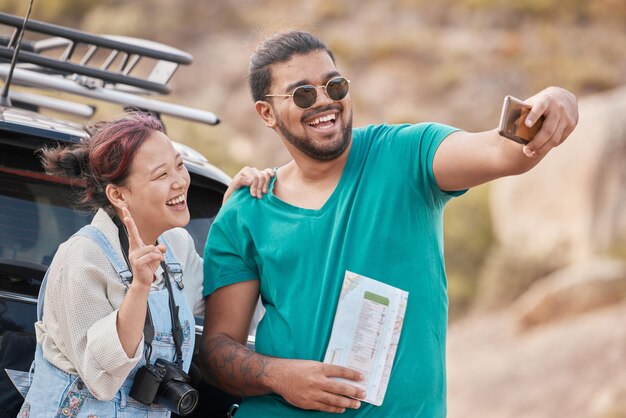 Photo couple travel and road trip selfie with peace sign map and smile while on a stop outdoor for social media streaming on vacation journey and adventure asian woman and man together for phone photo