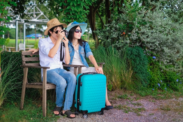 Il viaggiatore di coppia ha un bagaglio seduto sulla sedia e fotografa la natura