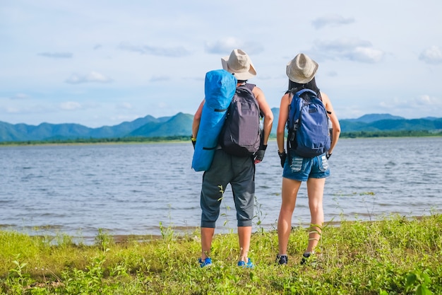 写真 湖の背景の近くに立っているカップル旅行者は山