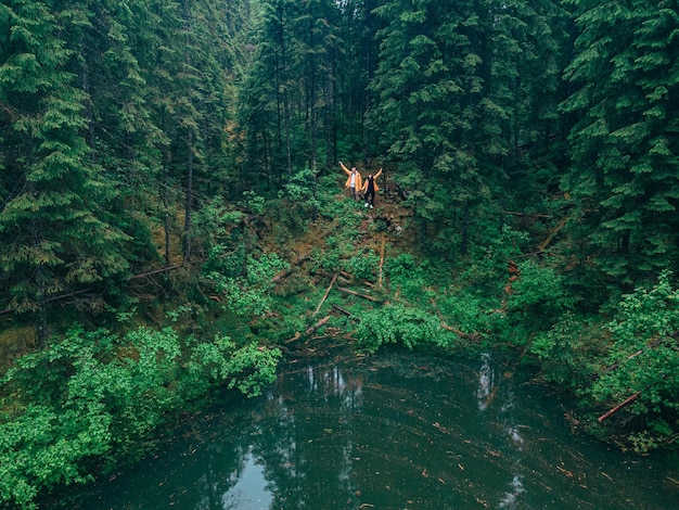 Couple travelers hikers reach mountain lake in forest copy space