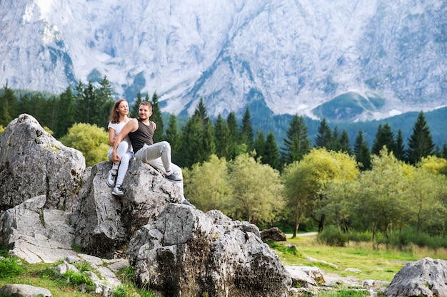 Couple of travelers on the Lago di Fusine lake with Mangart mountains in the background