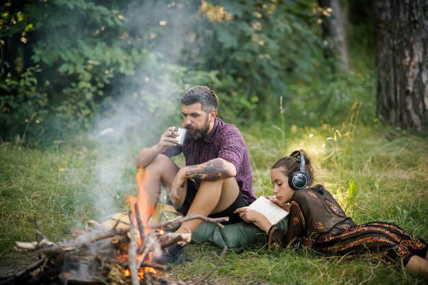 Couple of travelers relax at bonfire in forest