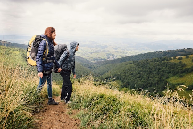 Пара путешественников с рюкзаками, смотрящих на холмы