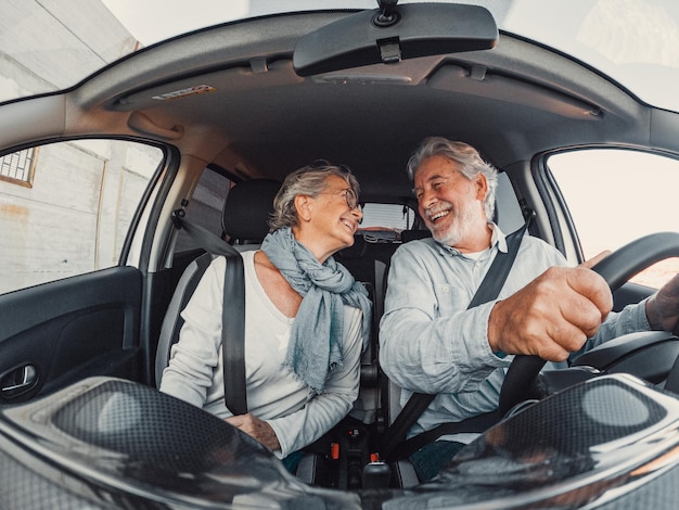 Una coppia di due anziani felici che si divertono e si godono le vacanze viaggiano insieme guidando e scoprendo nuovi posti con un'auto.