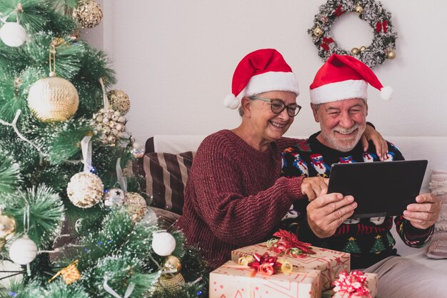 Couple of two seniors video calling their family at home celebrating christmas using laptop