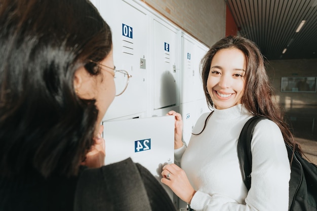 Couple of two young Female High School Students Talking By Lockers and saving and holding their material. Back to the university, study and learn concept. Exchange african students. Portrait