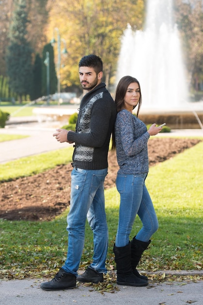 Couple Typing on Phone At Outdoor In Park