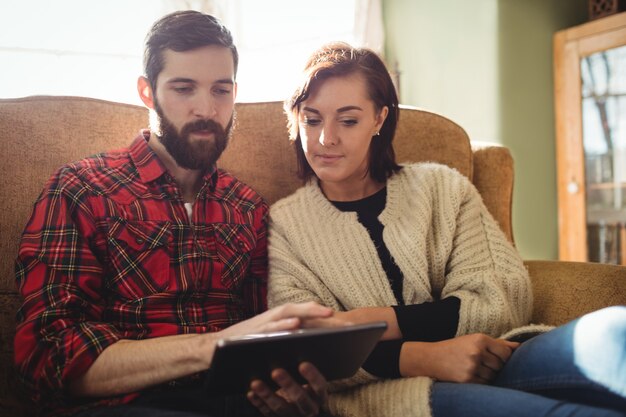 Couple using digital tablet in living room