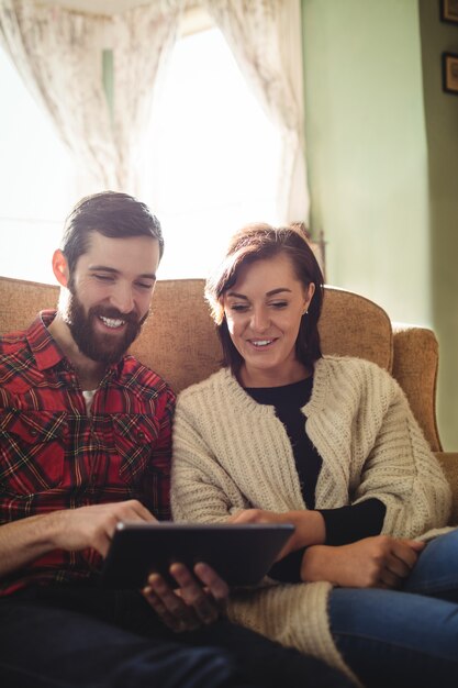 Couple using digital tablet in living room