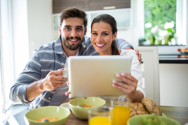 自宅で朝食をとりながらデジタルタブレットを使用してカップル