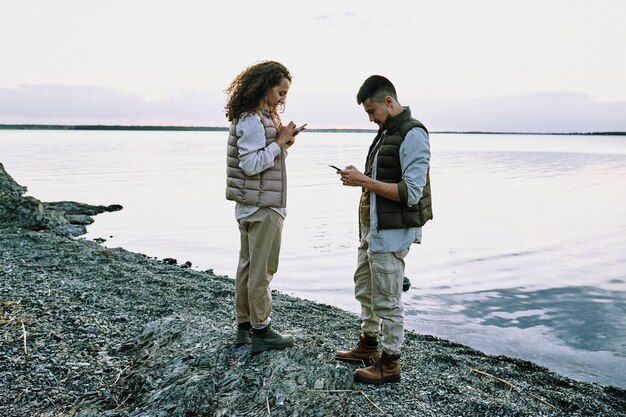 Couple using gadgets at lake