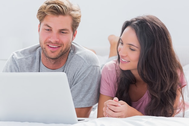 Couple using laptop in bed