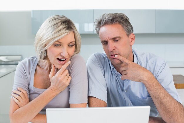 Couple using laptop in the kitchen