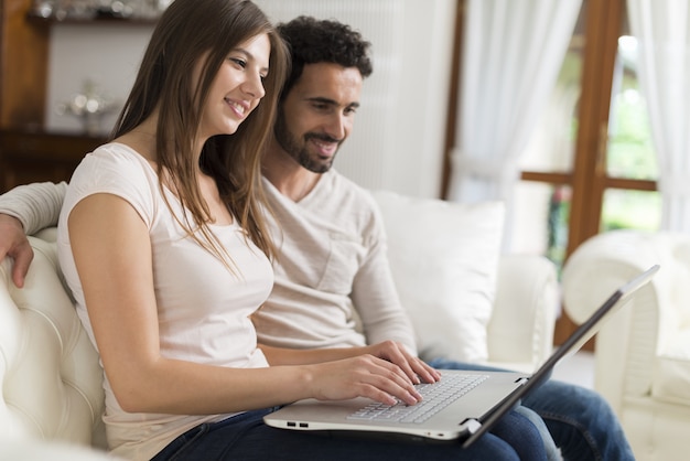 Couple using a laptop in their house living room