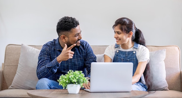 Couple using laptop together on the sofa in the living room