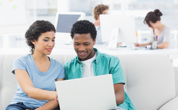 Couple using laptop with colleagues at creative office