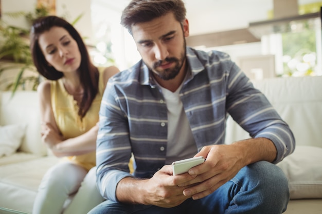 Couple using mobile phone on sofa