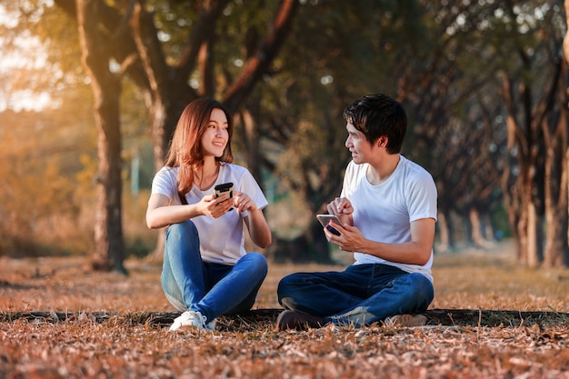 couple using mobile phone and talking in park