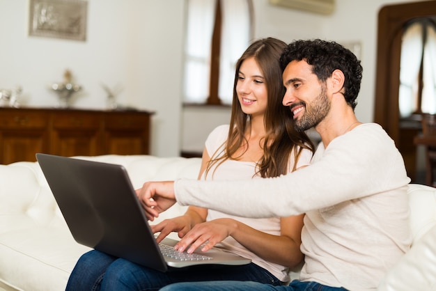 Couple using a notebook while relaxing on the couch