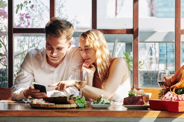 Photo couple using phone at dinner