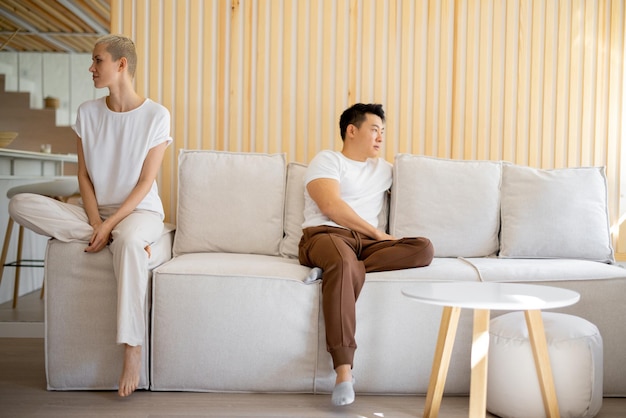 Couple using smartphones on sofa at home