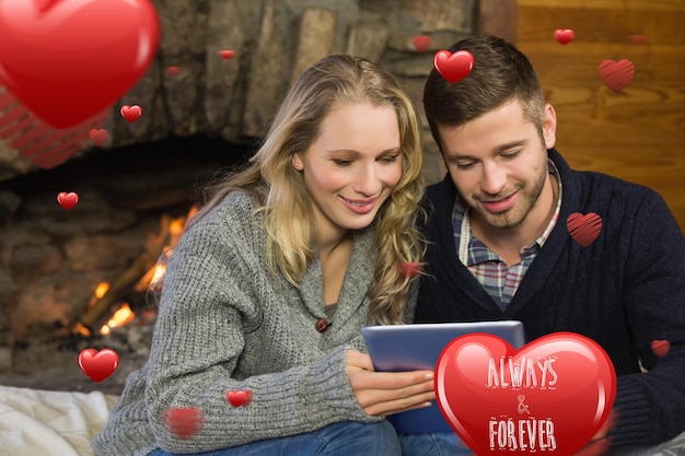 Photo couple using tablet pc in front of lit fireplace against always and forever