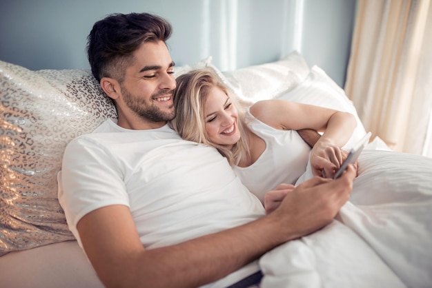 Couple using tablet in their bedroom