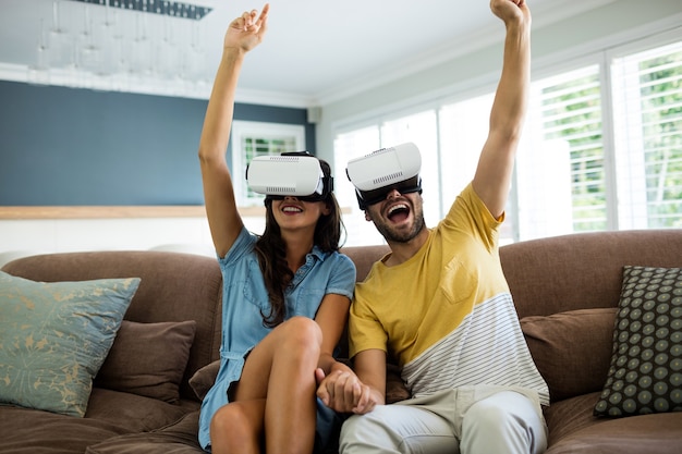 Couple using virtual reality headset in living room at home