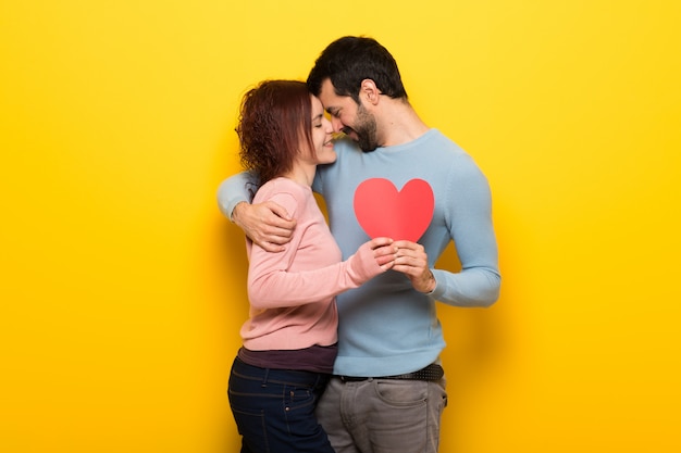 Couple in valentine day holding a heart symbol and kissing