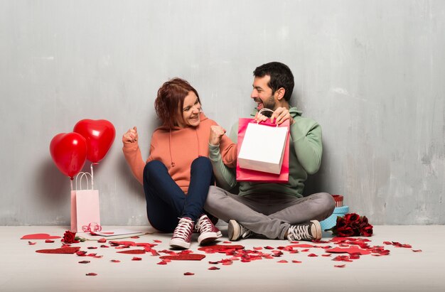 Photo couple in valentine day holding shopping bags in victory position