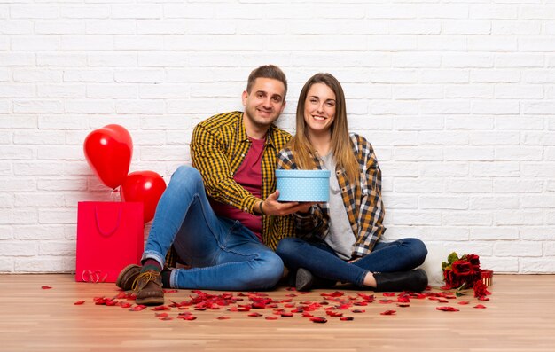 Couple in valentine day at indoors holding a gift in hands