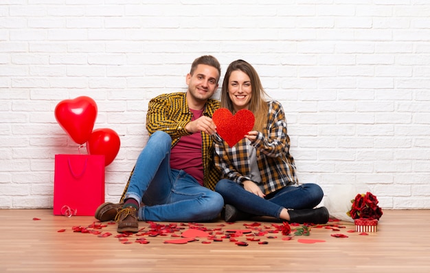 Couple in valentine day at indoors holding a heart symbol