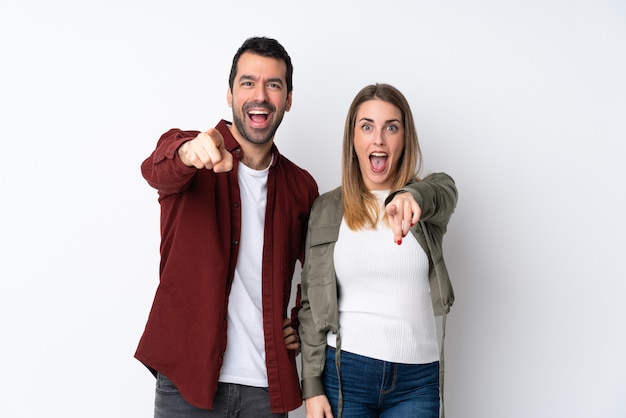 Couple in Valentine Day over isolated wall points finger to the front