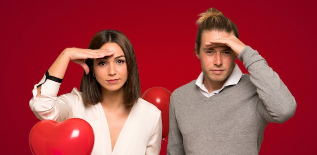 Couple in valentine day looking far away with hand to look something