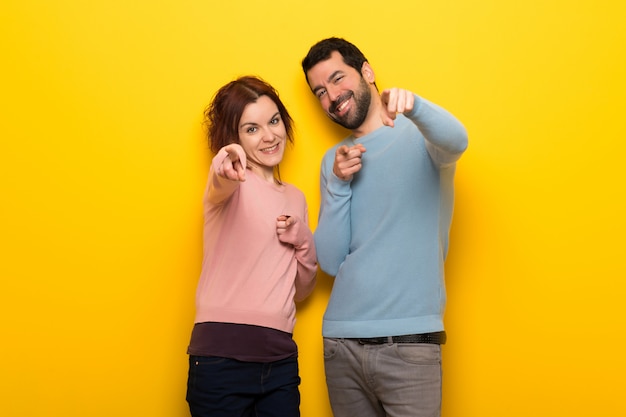 Couple in valentine day points finger at you with a confident expression