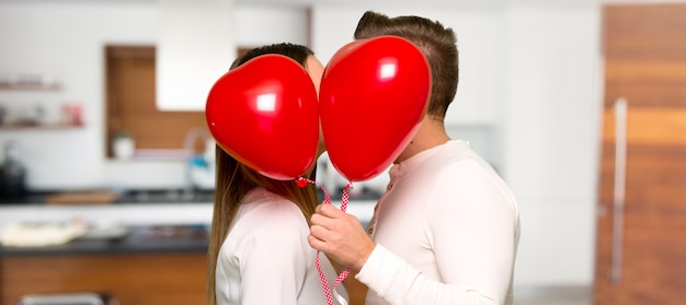 Couple in valentine day with balloons with heart shape in a house