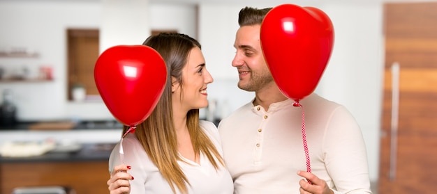 Couple in valentine day with balloons with heart shape in a house