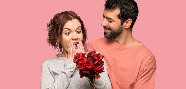 Couple in valentine day with flowers over isolated pink background