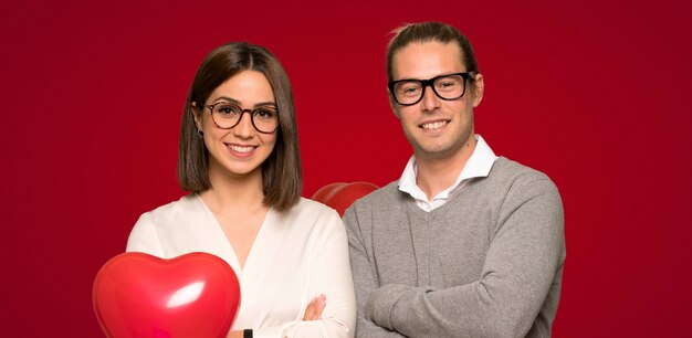 Couple in valentine day with glasses and happy over red background