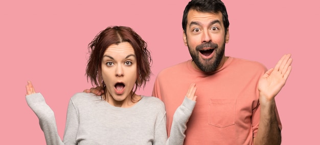Couple in valentine day with surprise and shocked facial expression over isolated pink background