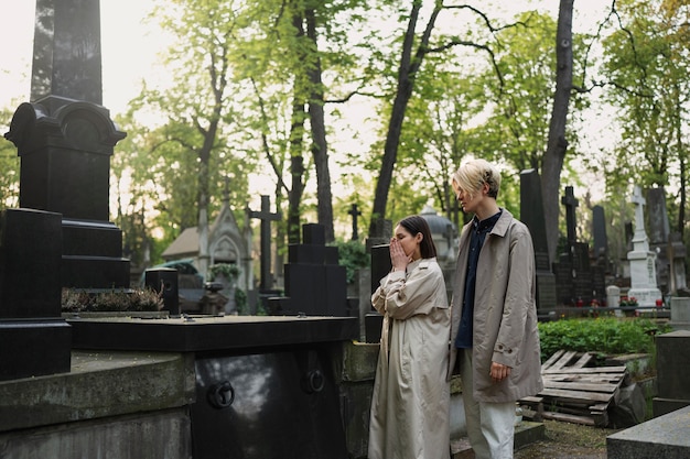 Photo couple visiting a grave together at the cemetery