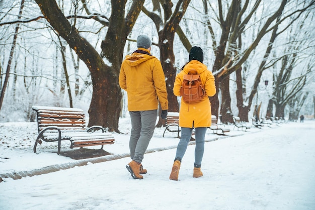 雪に覆われた都市公園のそばを歩いているカップルが社交的に話している。冬時間のロマンチックなデート。クリスマスが来ています