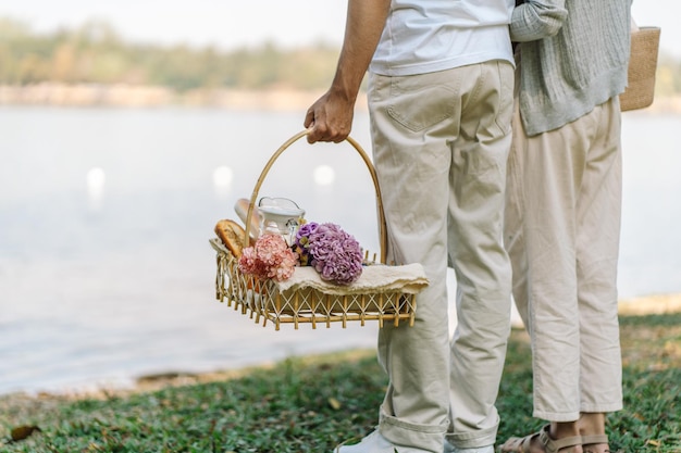 Couple walking in garden with picnic basket in love couple is enjoying picnic time in park outdoors