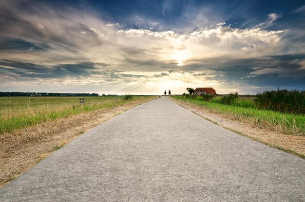 couple walking on path over dramatic sky