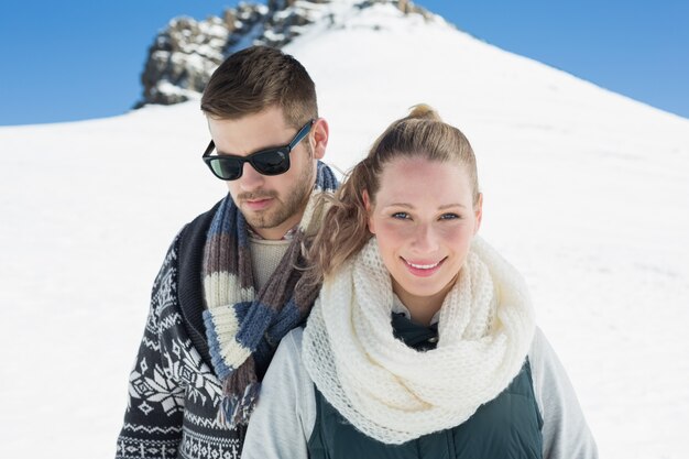 Couple in warm clothing in front of snowed hill