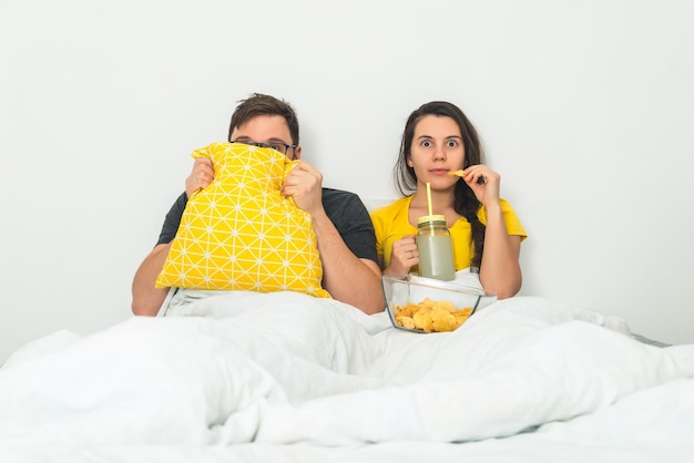 Couple watch scary movie in bed